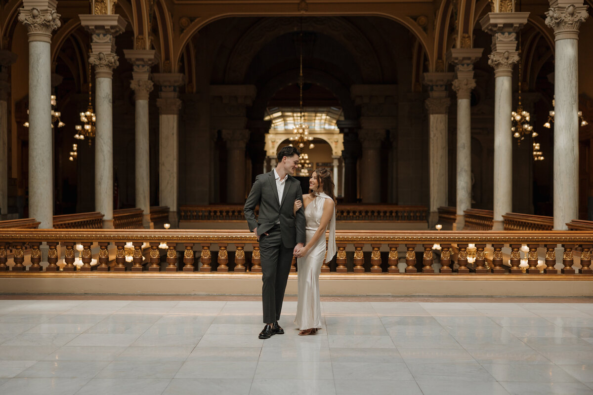 The photo shows a couple who are engaged standing in the Indianapolis State House in dressy clothing. This was for an engagement photoshoot,