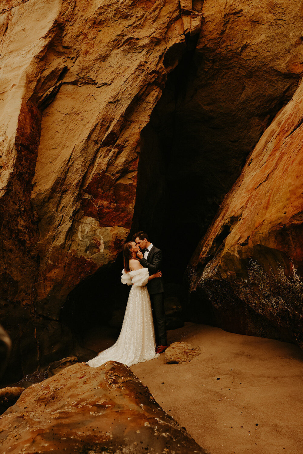 Bride and groom kissing under a rock formation