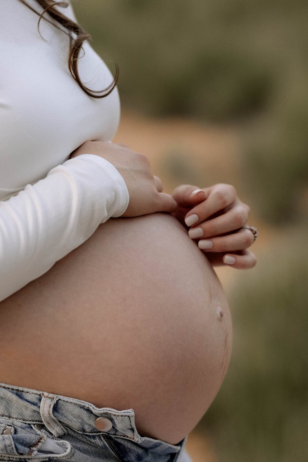 photo of pregnant belly, mama's fingertips lightly touching her belly