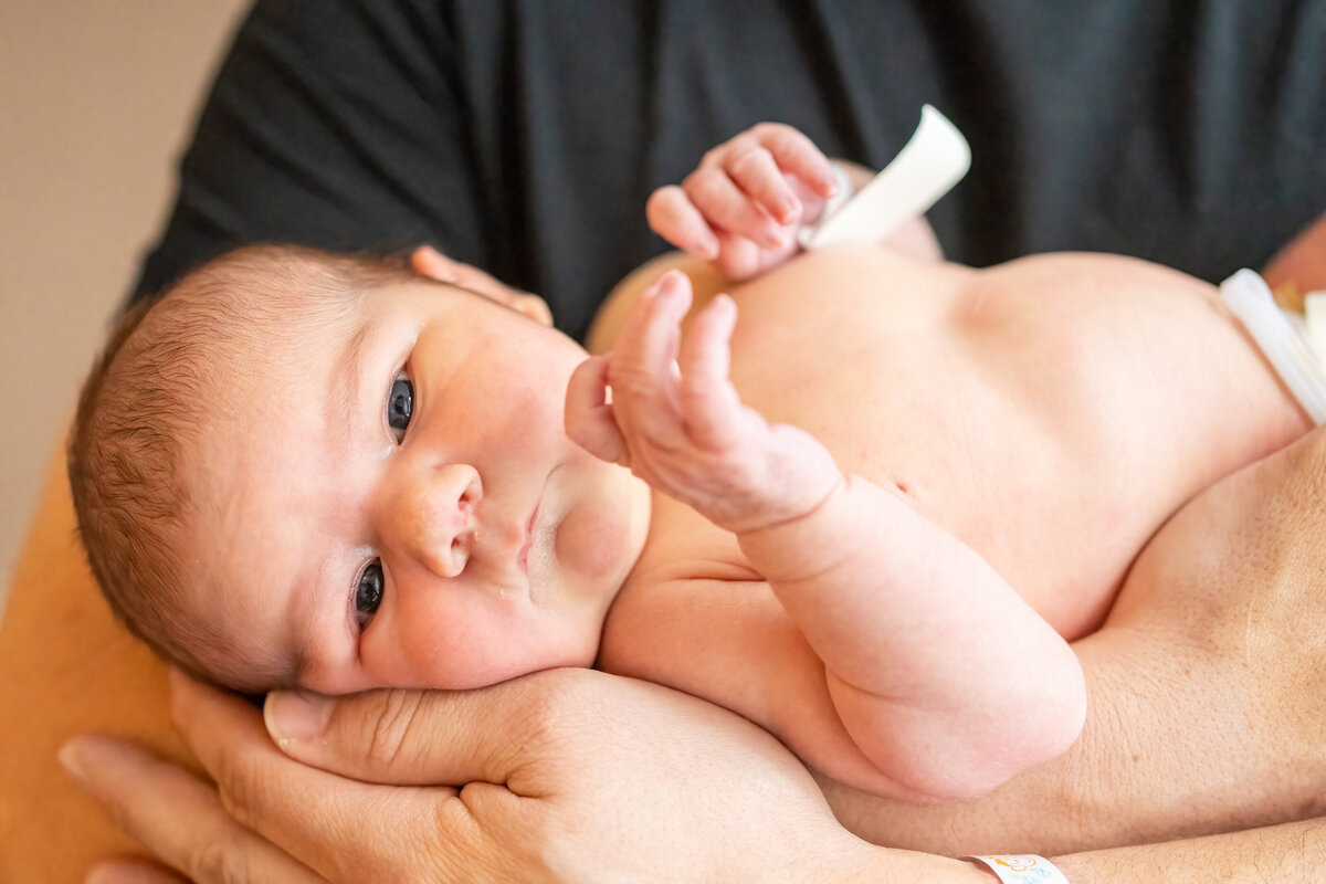 Newborn baby laying in dad's arms