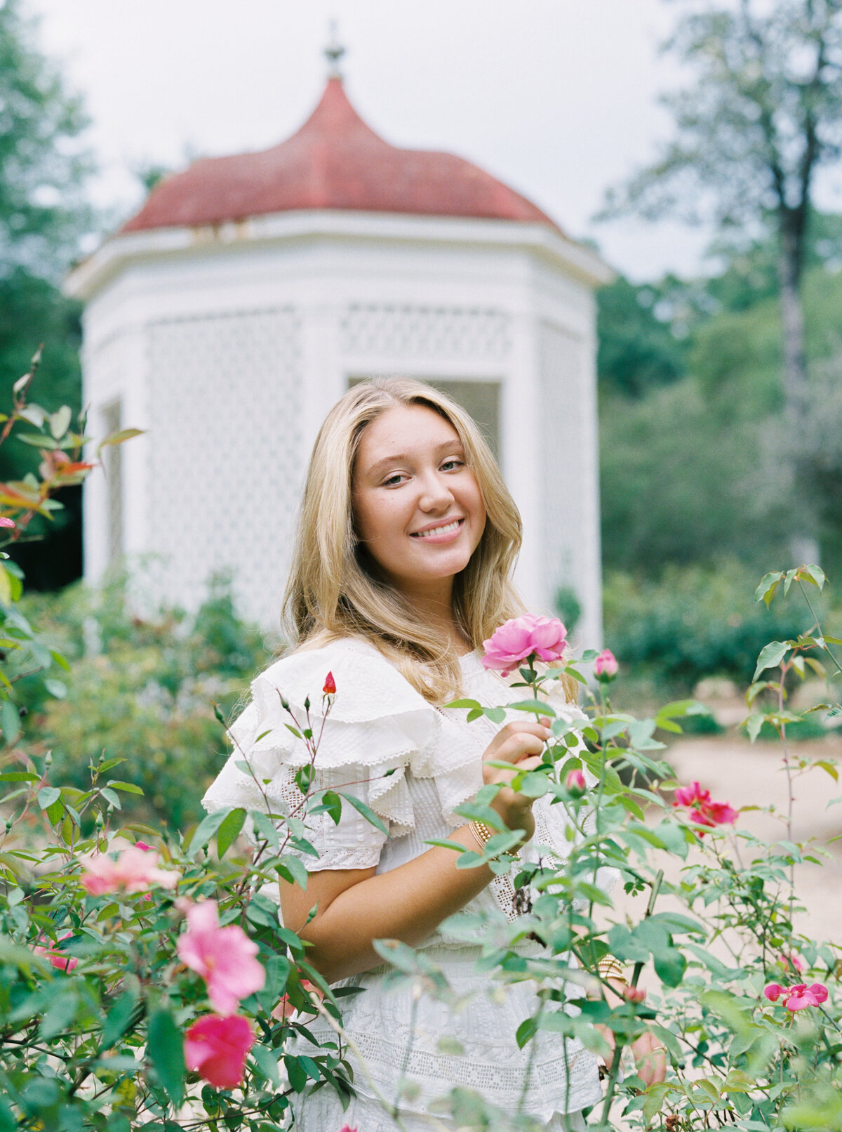 A senior portrait in the lush gardens of Rosedown Plantation, showcasing charm and elegance amid beautiful blooms, captured on film by Morgan Alysse, Louisiana film photographer.
