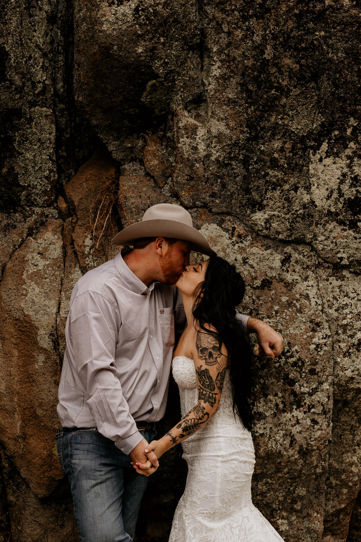 bride and groom kissing against a rock in New Mexico