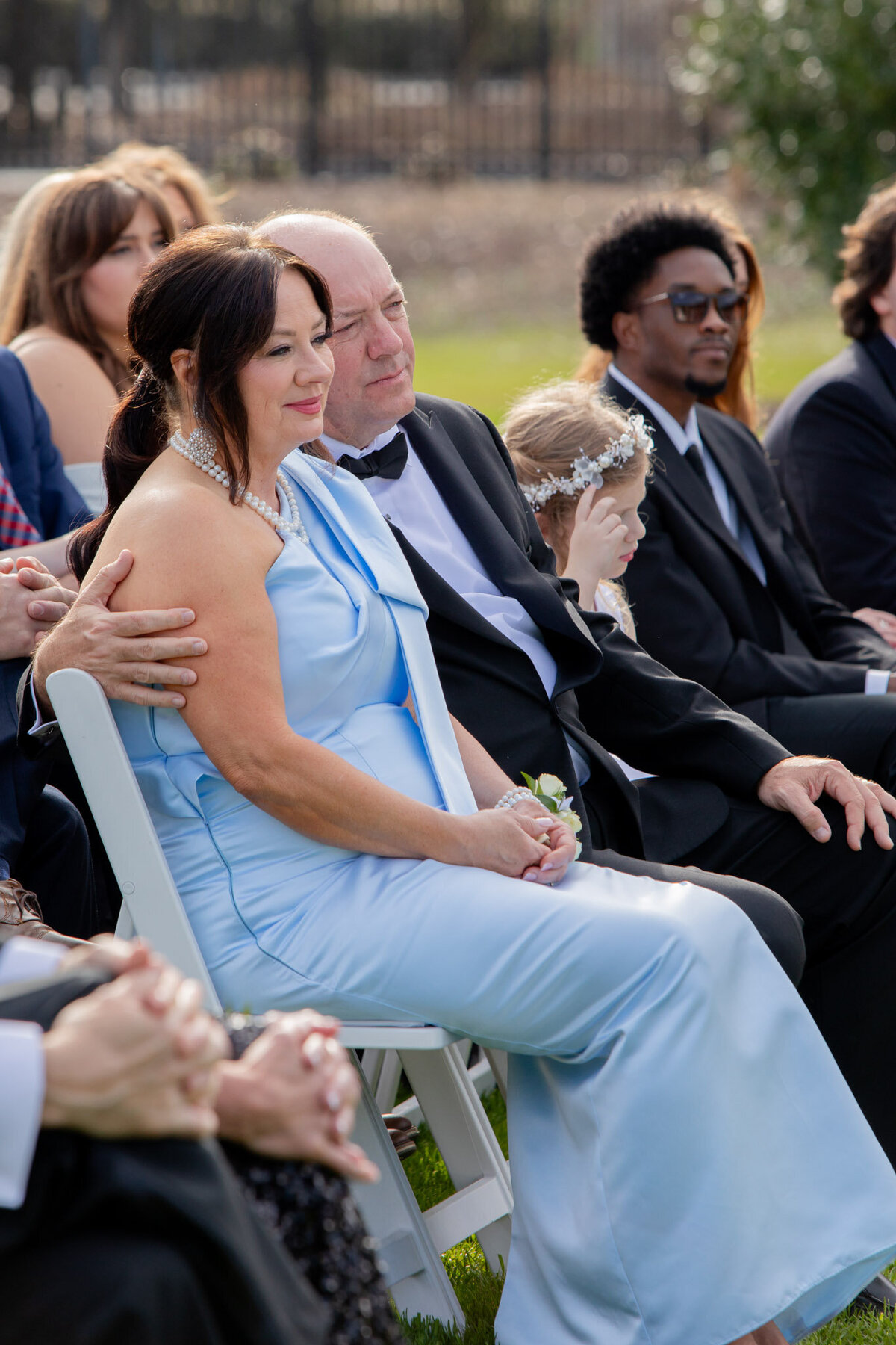 A shot of the audience during a wedding ceremony, the main focus being the mom and dad of either the bride or groom.