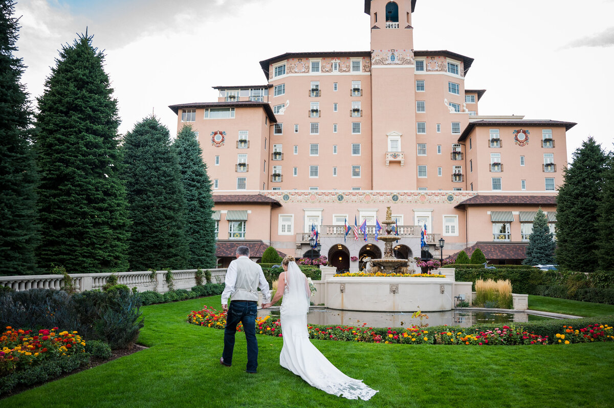 A groom leads his bride toward the Broodmoor Hotel in Colorado Springs, Colorado.