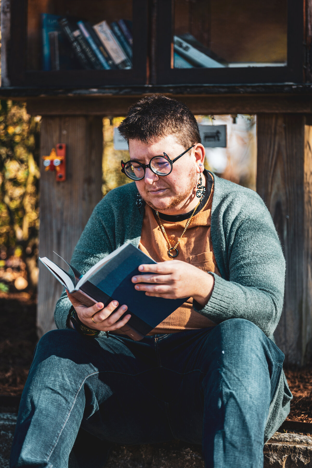 A person reading a book in front of a free library in Durham, North Carolina.