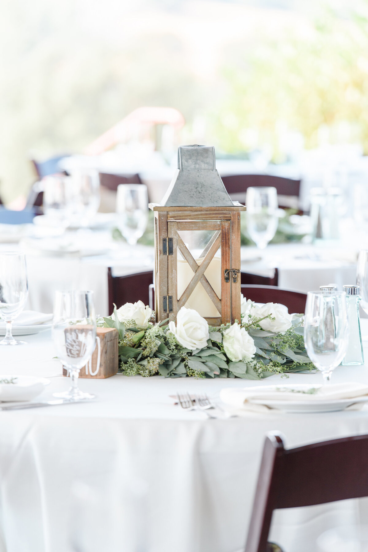 table with a wood lantern white flowers and greenery