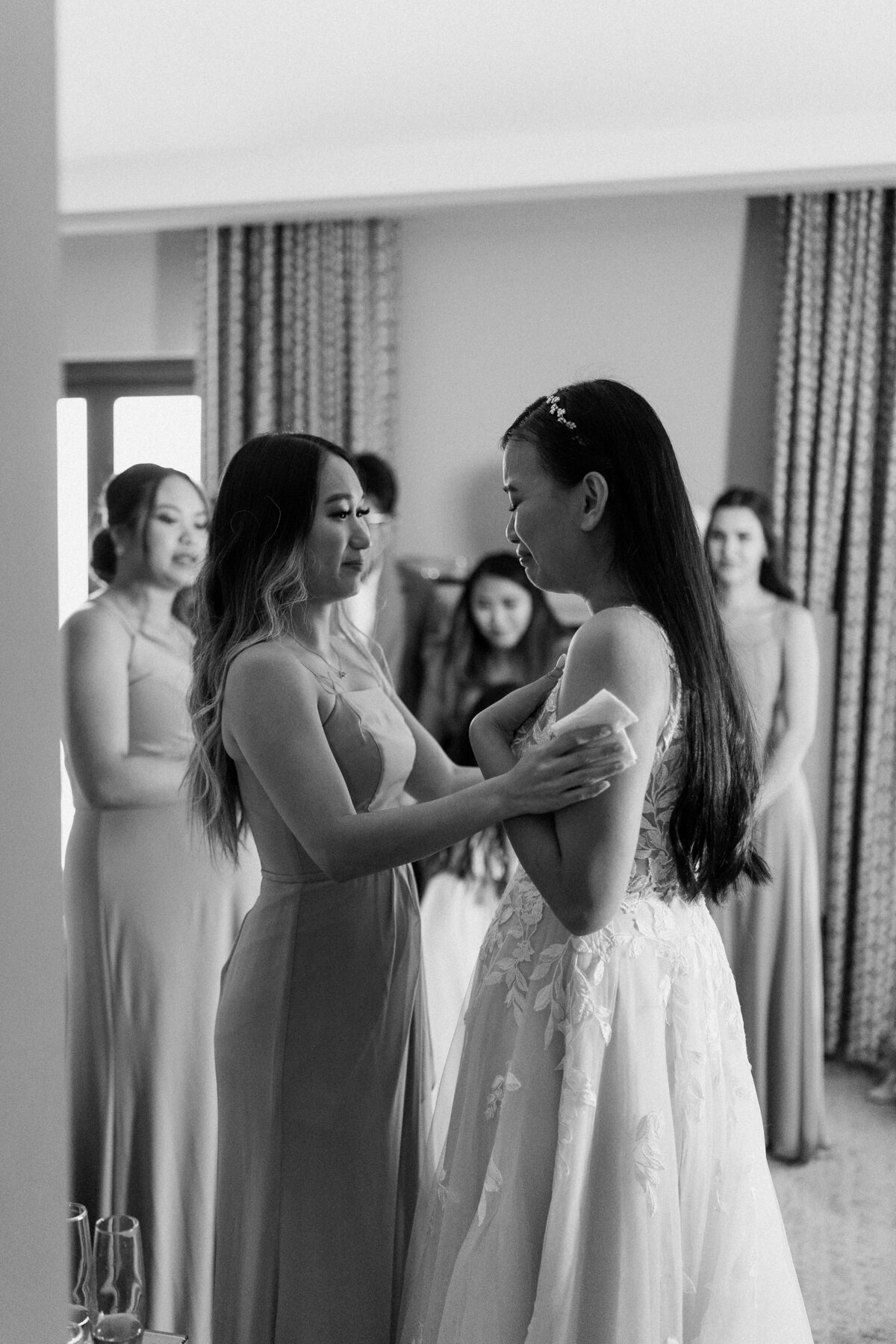 bride crying as she  shows her wedding dress to her bridesmaids 