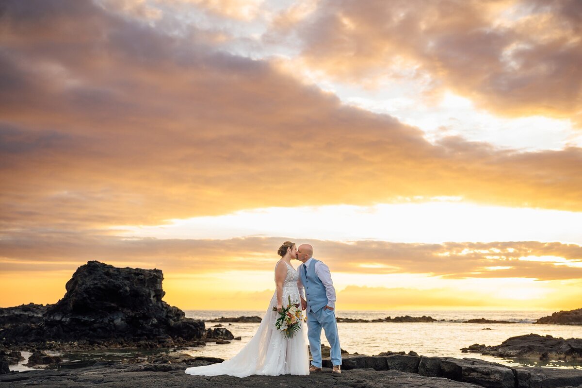a newlywed kiss with a stunning Hawaii sunset as a backdrop