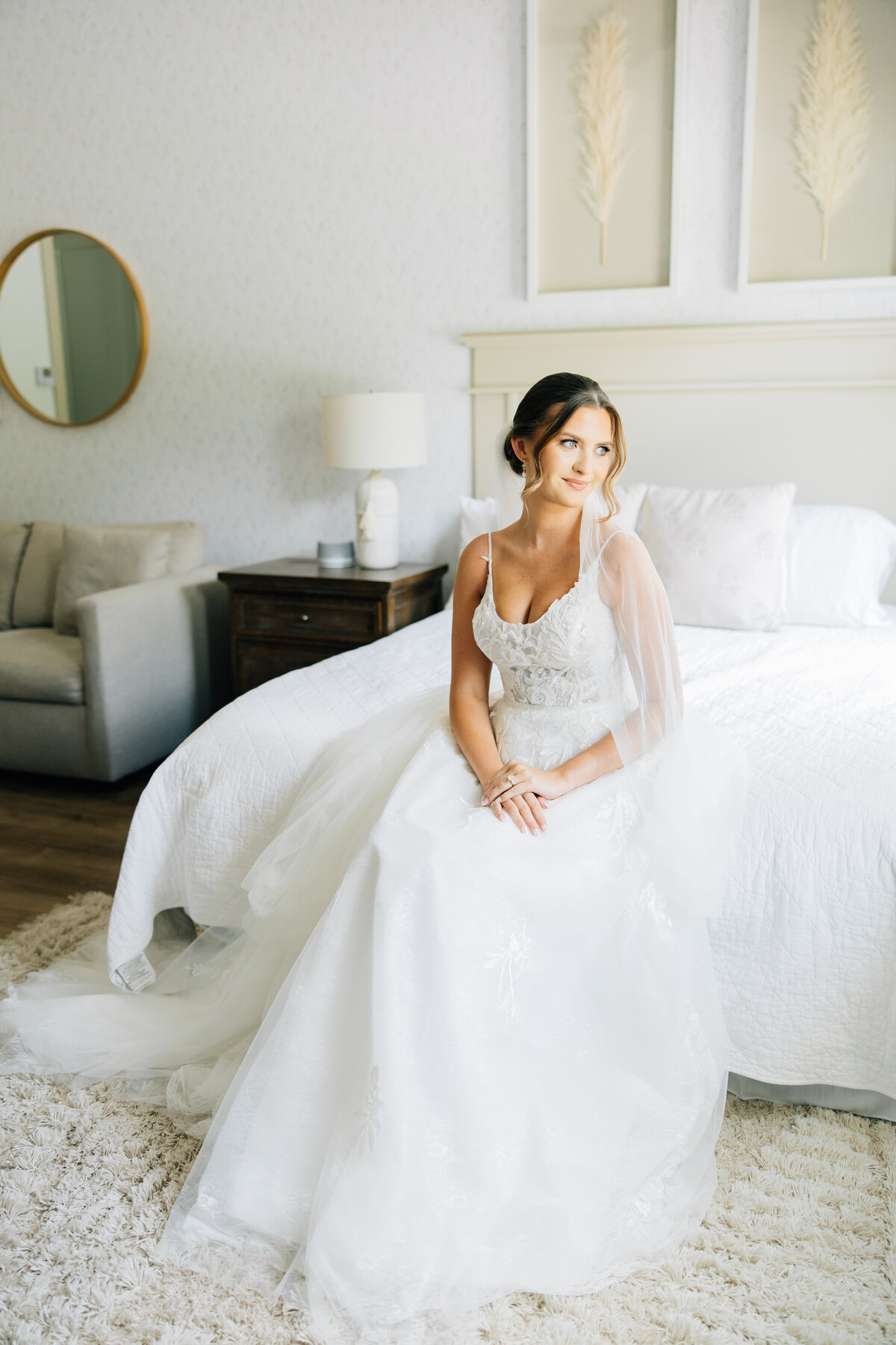 bride sitting on a bed in her wedding dress looking deep in thought