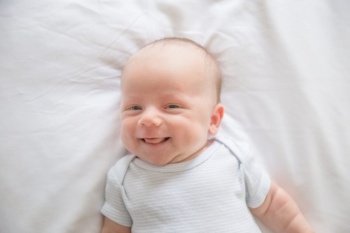 laughing newborn baby boy on a white bed