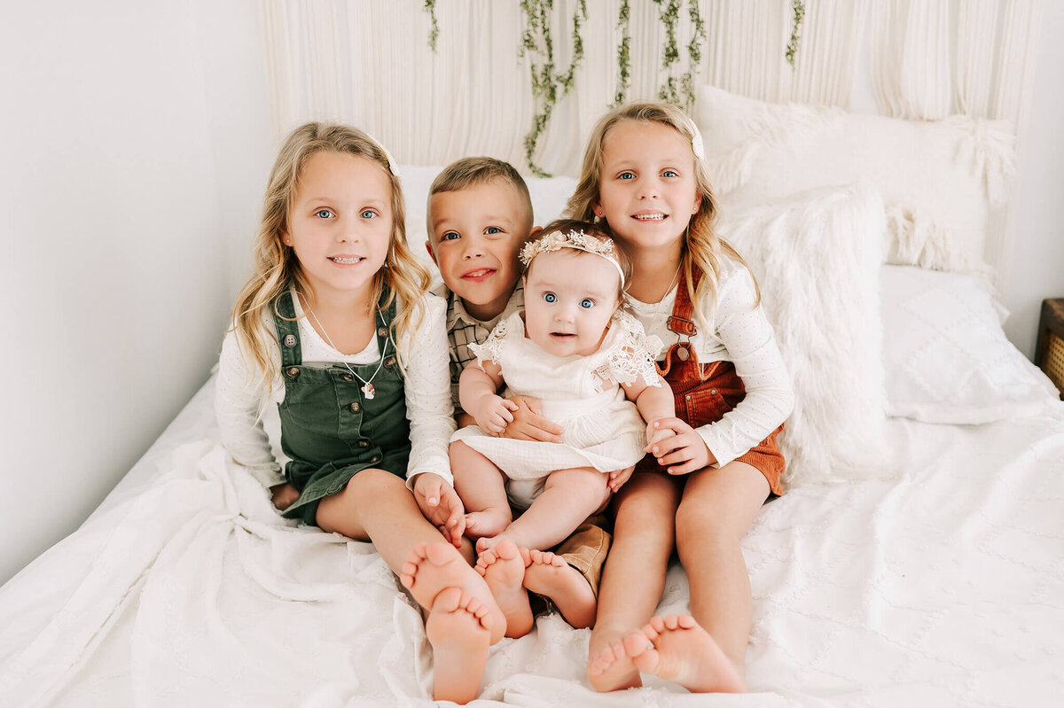 kids cuddling in bed smiling during Springfield MO family photography