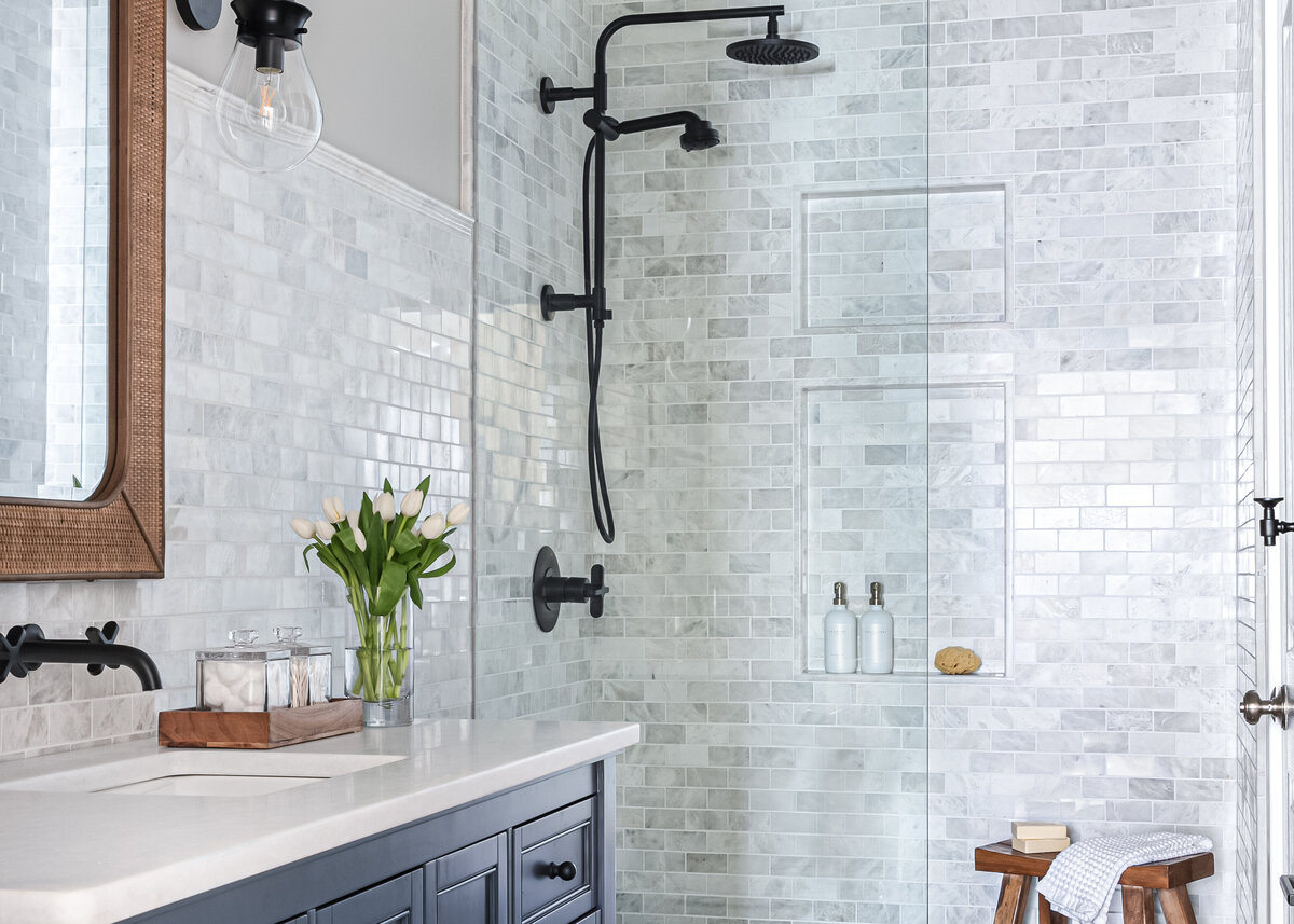 Transitional bathroom with blue cabinets, marble subway tile, and black fixtures.