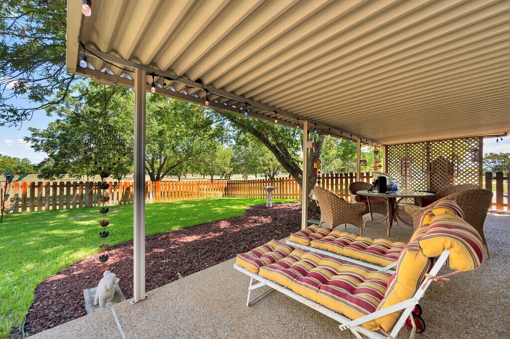 Large covered patio with comfortable seating and gas grill at this three-bedroom, two-bathroom vacation rental home with hot tub, firepit, and free WiFi just minutes from Lake Waco.