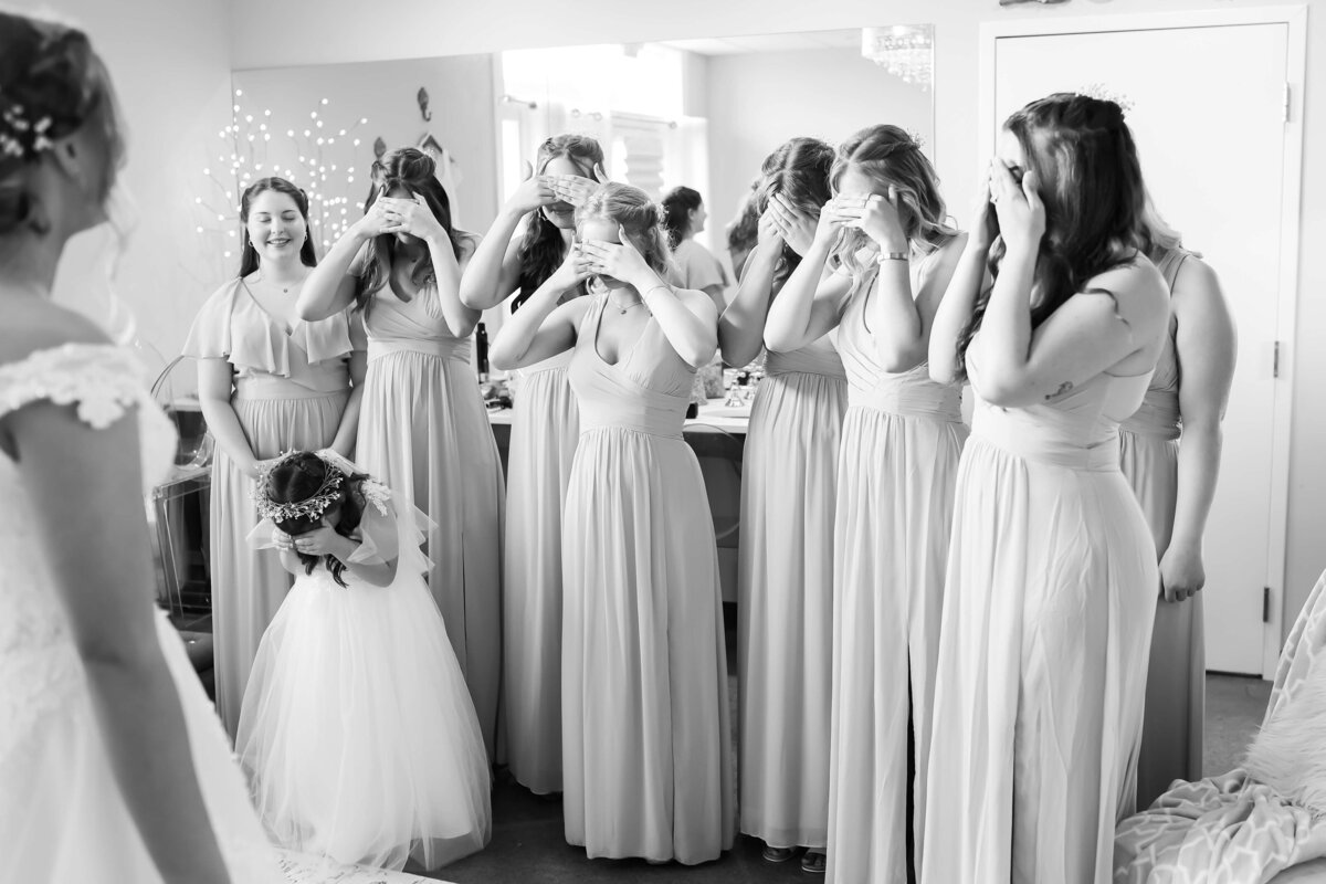 Bridesmaids covering their eyes before they see bride in dress