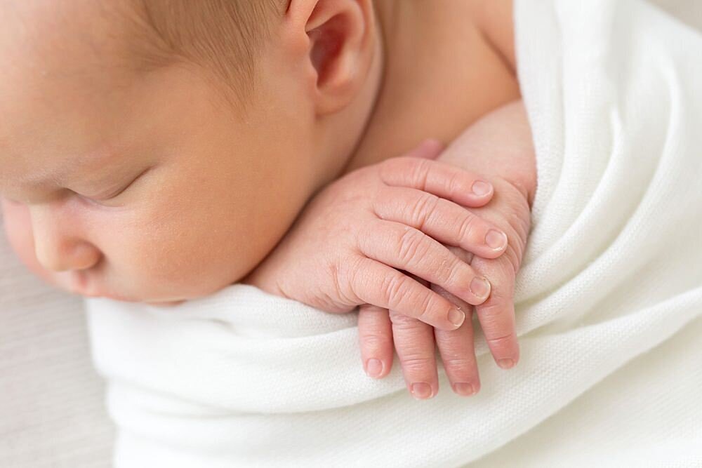 Sleeping baby swaddled with hands out by Louisville Portrait Photographer