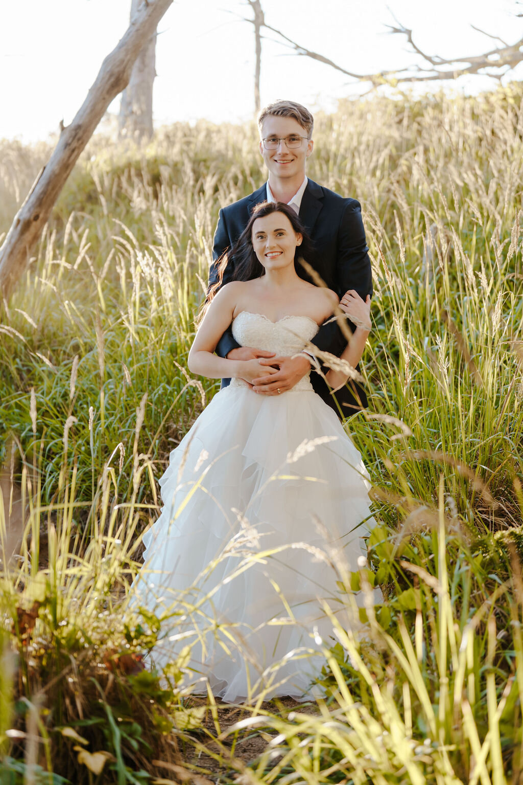 a bride and groom embracing in a field