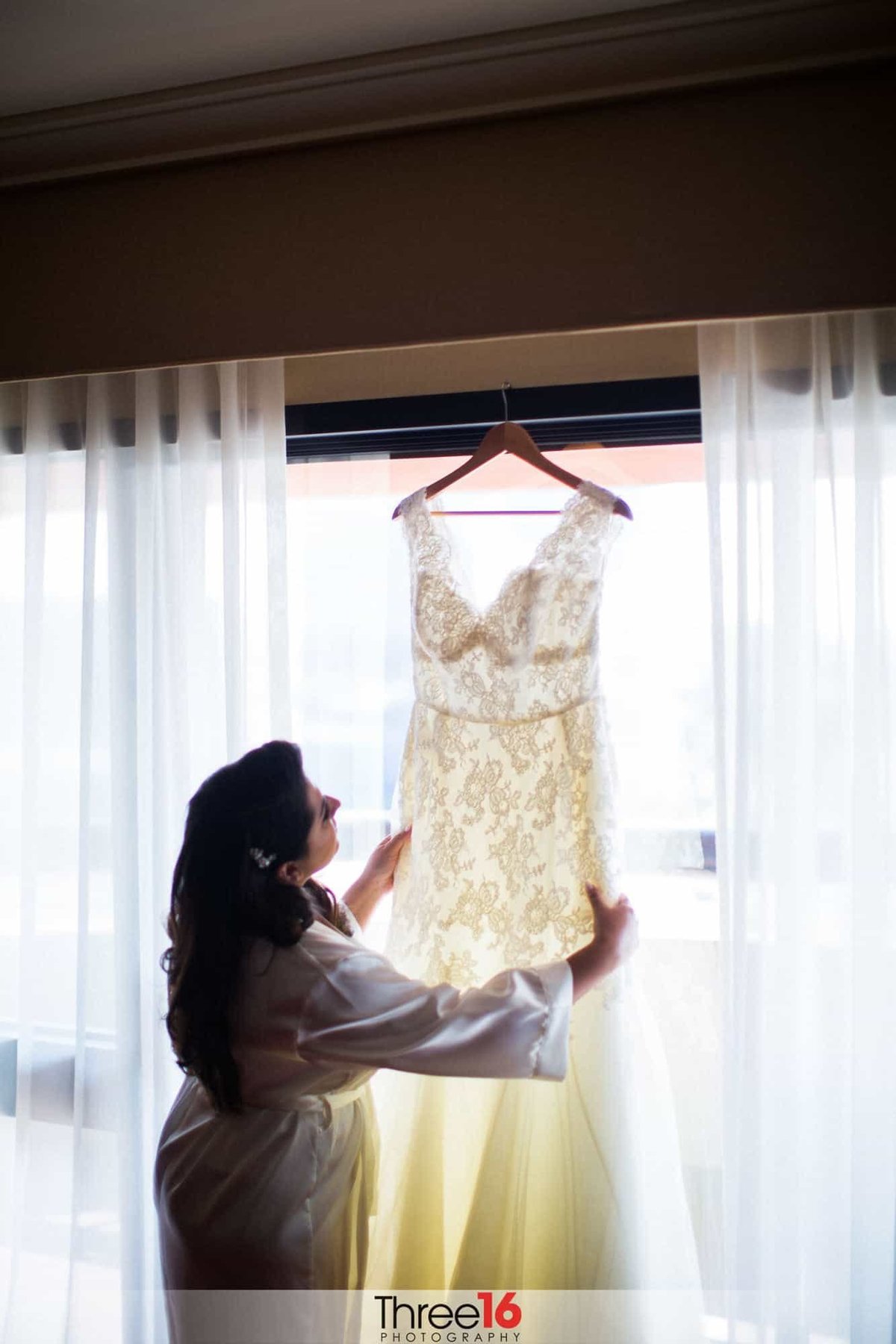 Bride looks at her dress as it hangs on the rod