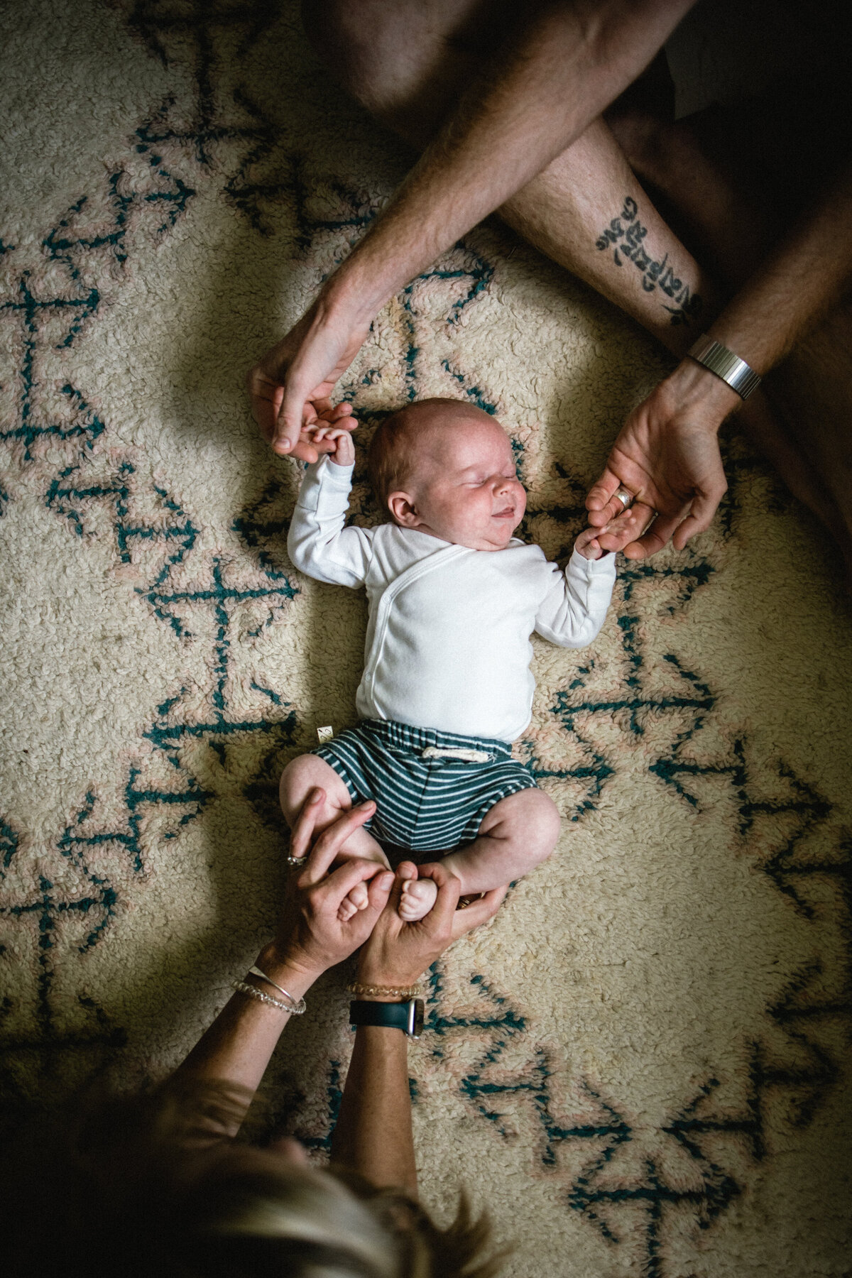 Mom and dad holding newborn baby's fingers and toes on floor