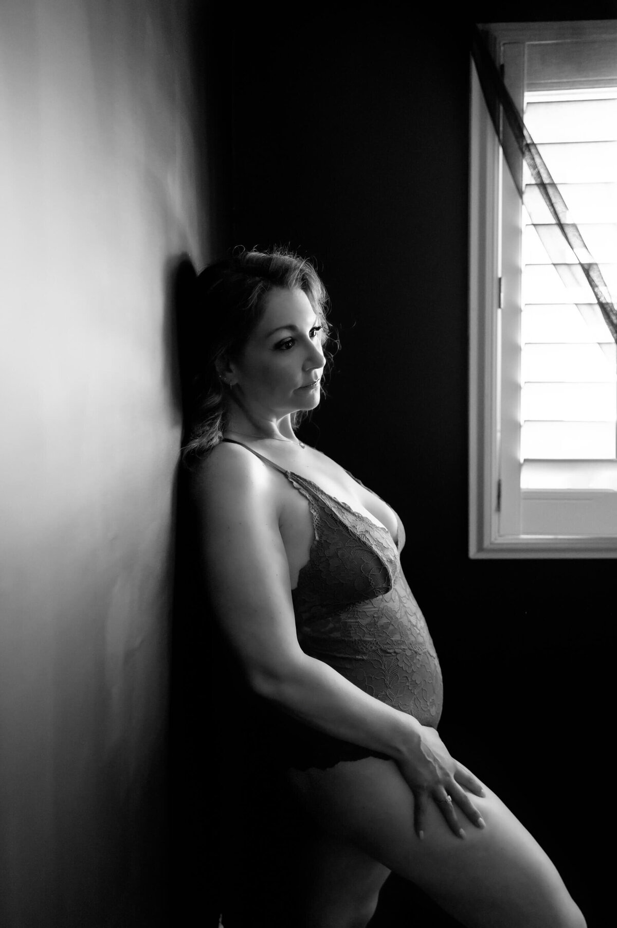woman leaning against a wall for her luxury boudoir photos.