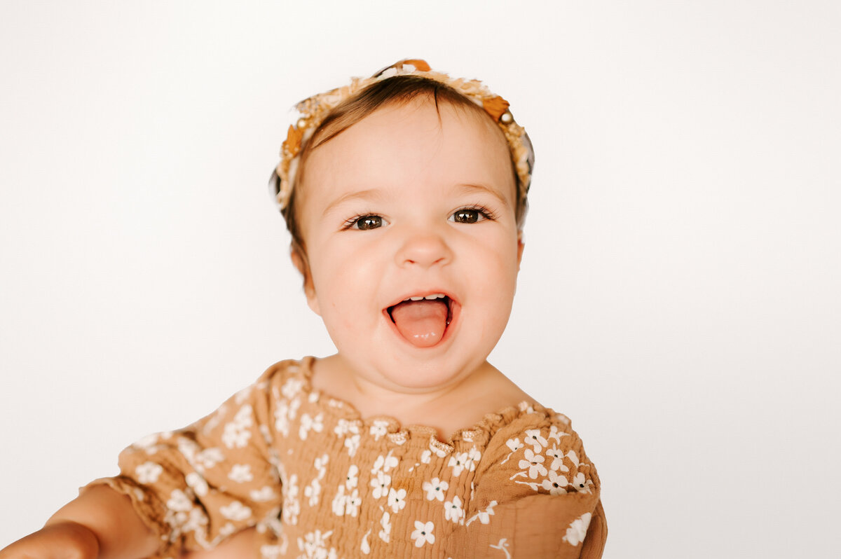 girl sticking out her tongue smiling during her Springfield MO kids photography session during her 1st birthday milestone