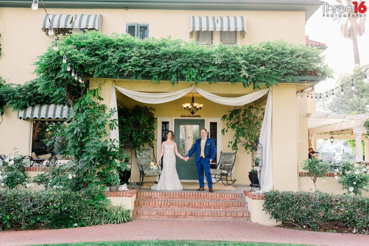 Newly married couple pose on the porch of The French Estate Wedding Venue