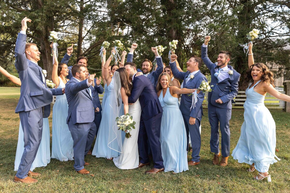 Bridal party cheering around bride and groom as they share a kiss