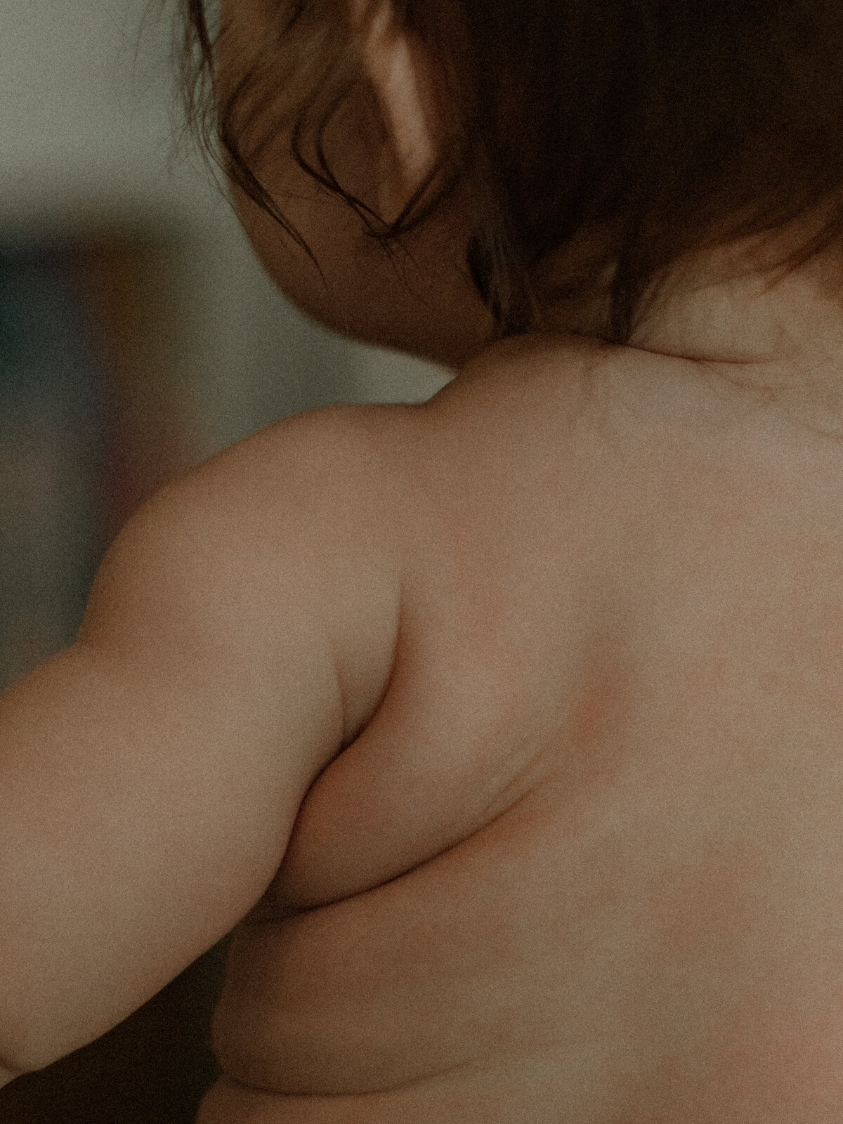 Close-up of a baby’s soft shoulder and neck, capturing the natural texture of baby skin in warm light.