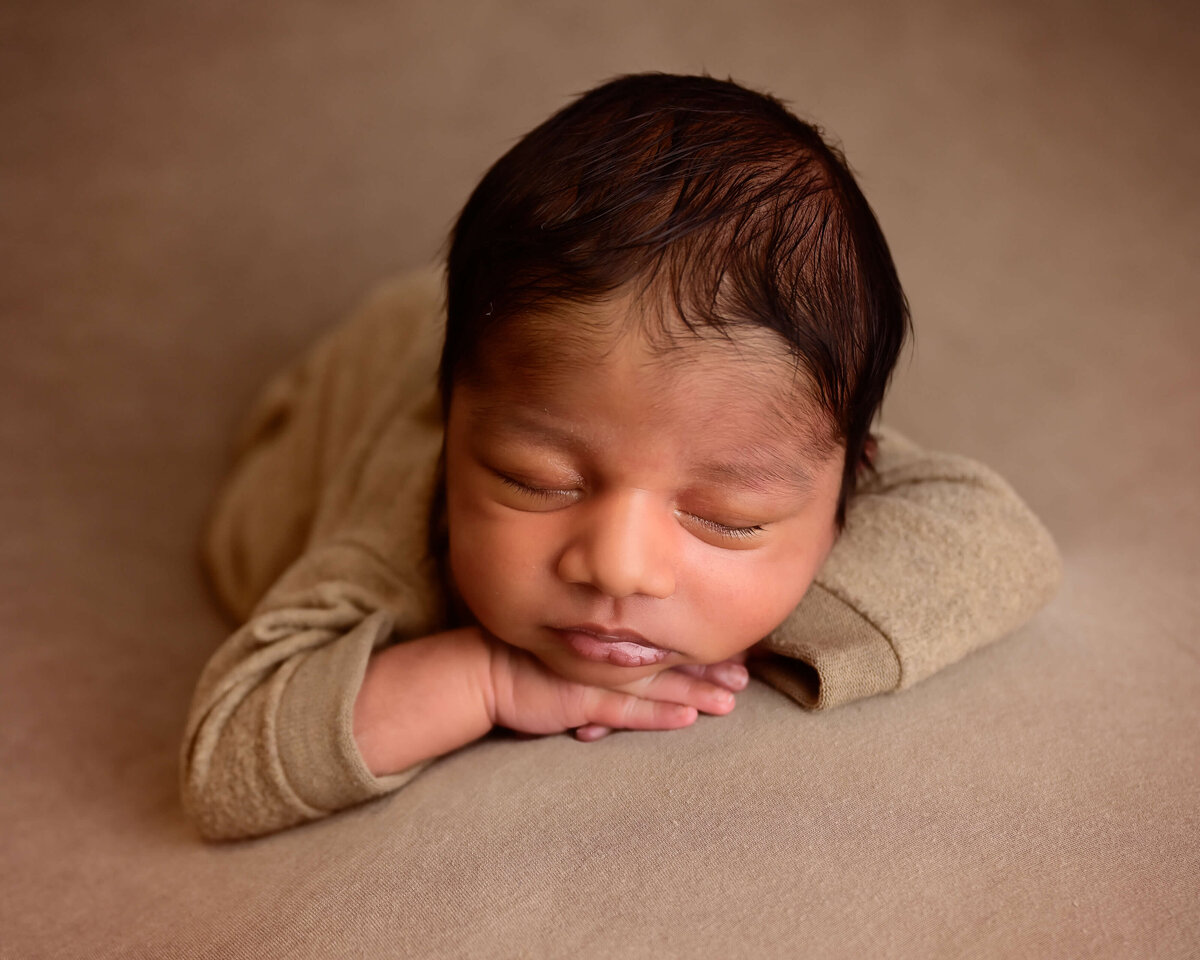 Kitsap newborn session with newborn posed sleeping on his belly with his hands under his chin. Image captured by Beth Benecki.