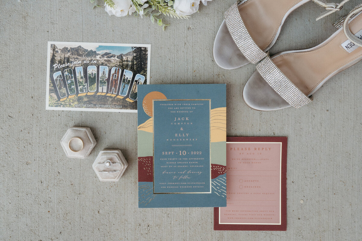 Wedding details with a Colorado postcard save the  date, and slate blue sunset invitation, velvet white ring box, and light pink detail card.