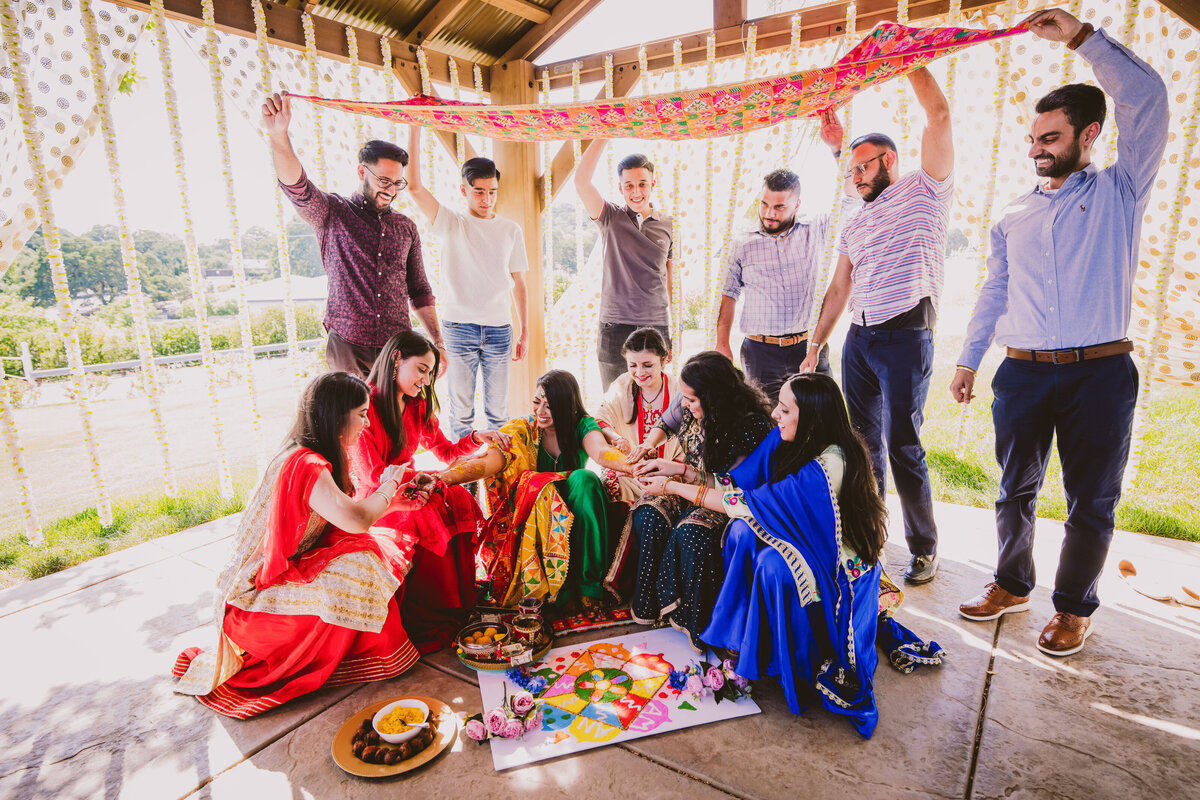 indian sikh bridesmaids putting haldi on the bride during the maiyaan ceremony