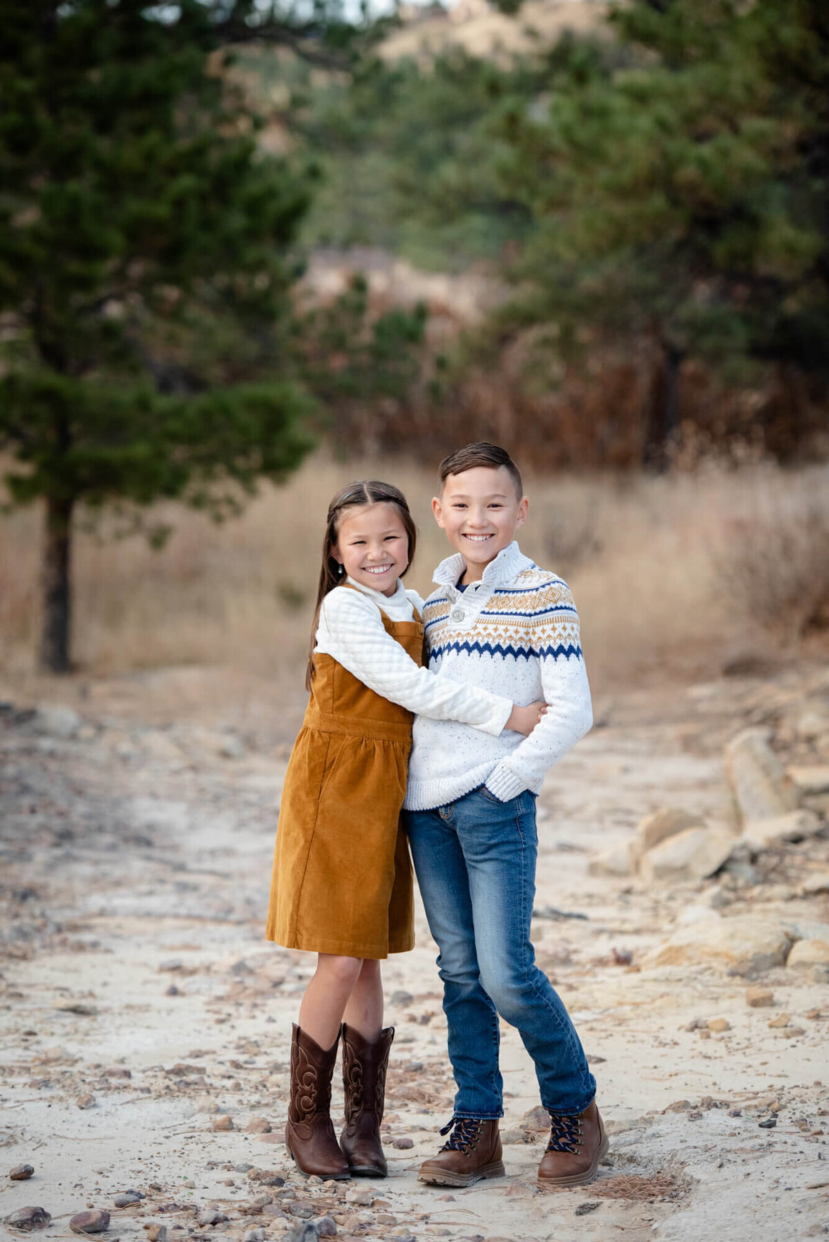 An image of brother and sister hugging while standing in a rocky trail by a Colorado Springs family photographer