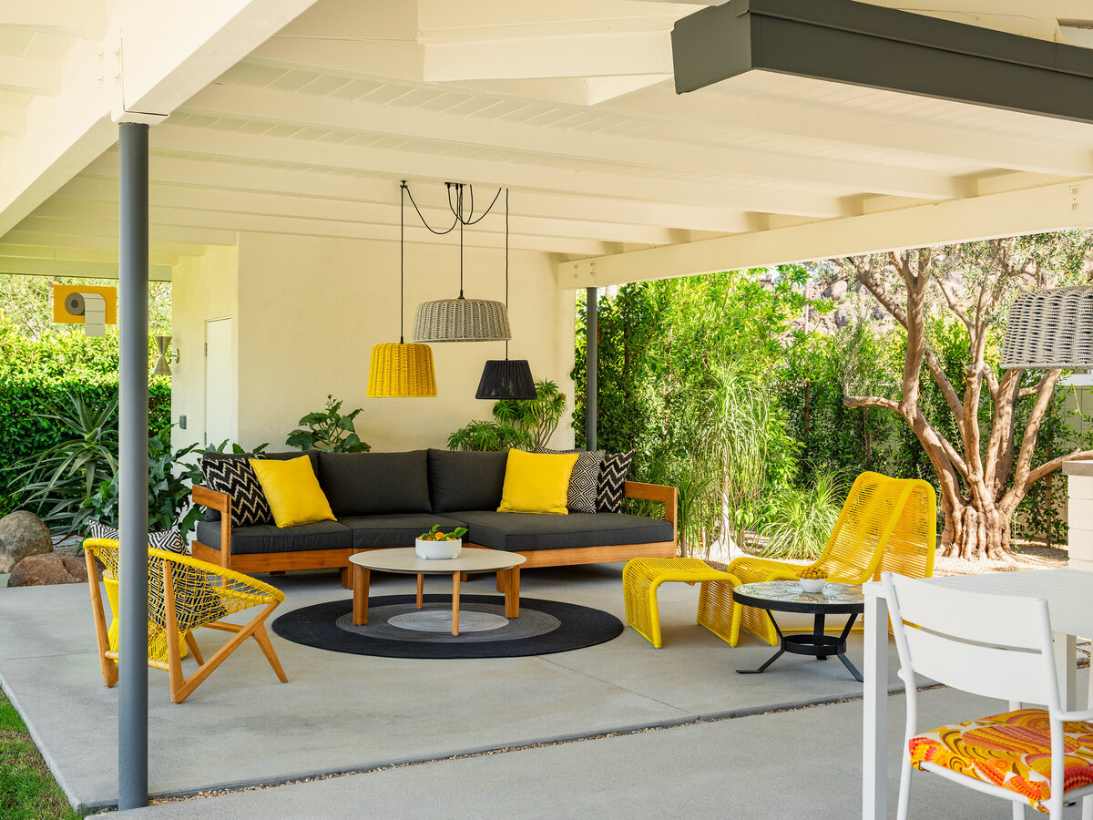Outdoor cabana with yellow modern furniture and surrounded by lush desert landscape designed by Los Angeles architect.