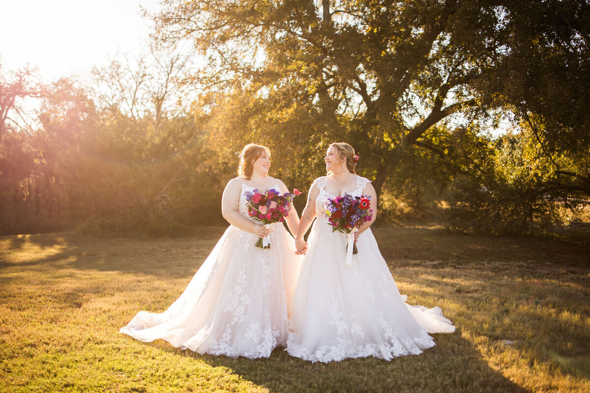 Bride and bride holding each others hand and holding their floral bouquets