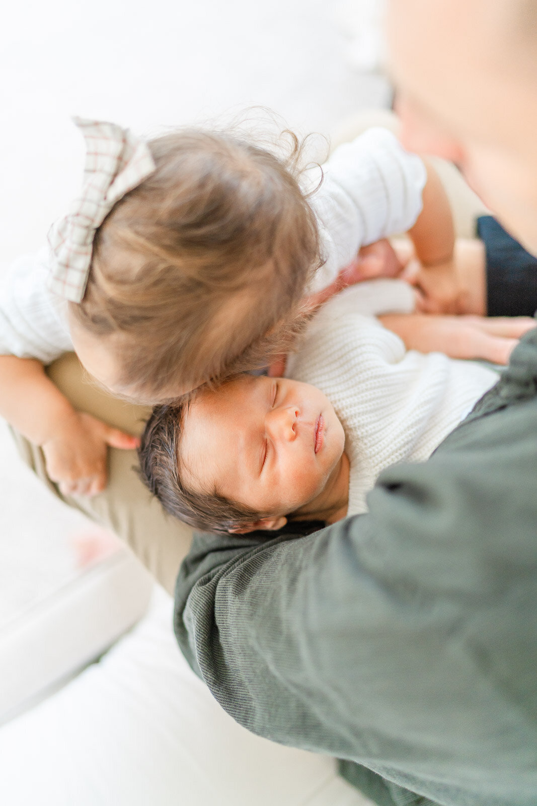 a newborn boy is kissed on the forehead by his sibling during his lifestyle newborn session in their Round Rock home.
