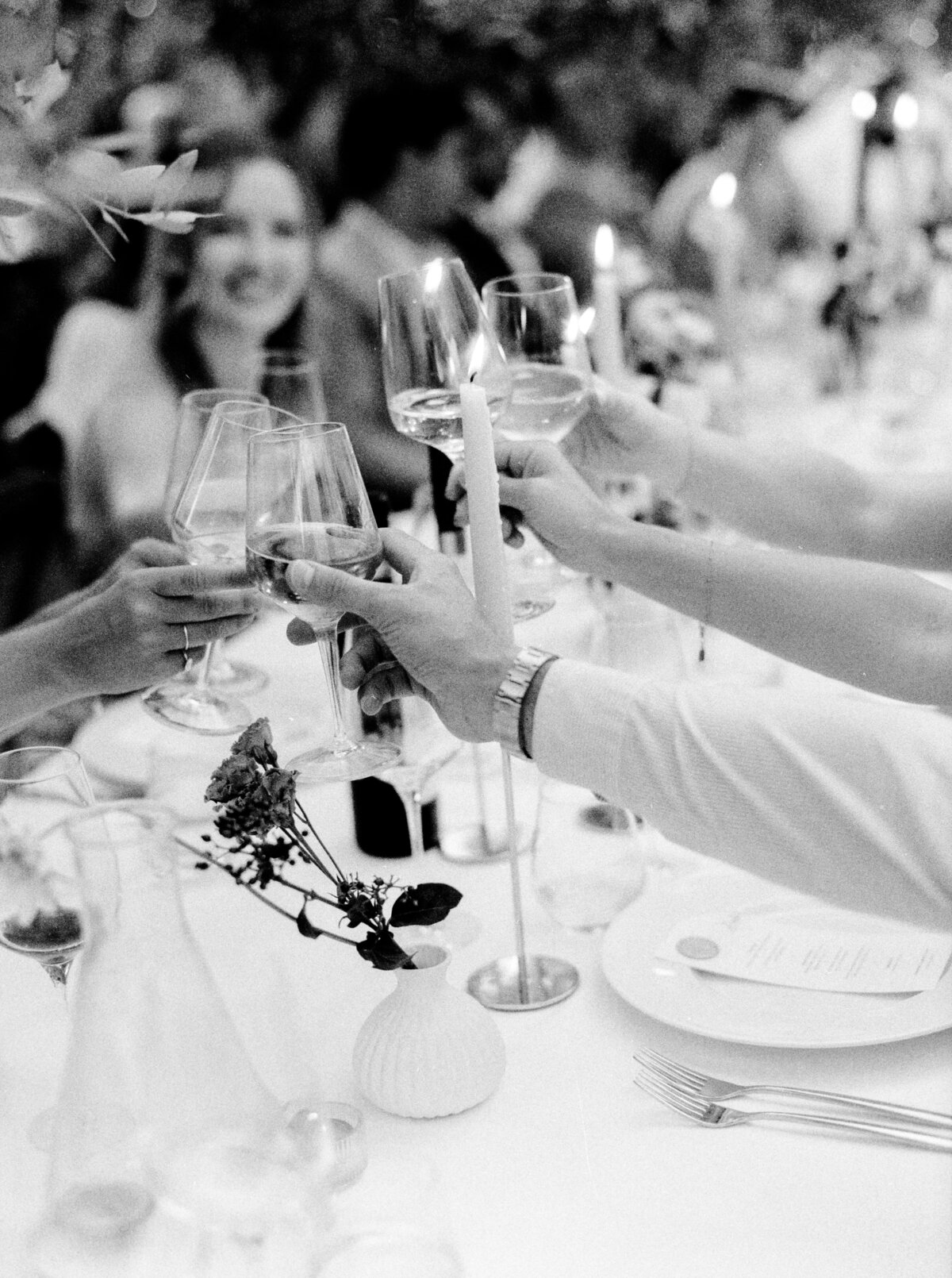 Black and white film photograph of Guests at wedding reception cheers'ing photographed by Italy wedding photographer at Villa Montanare Tuscany wedding