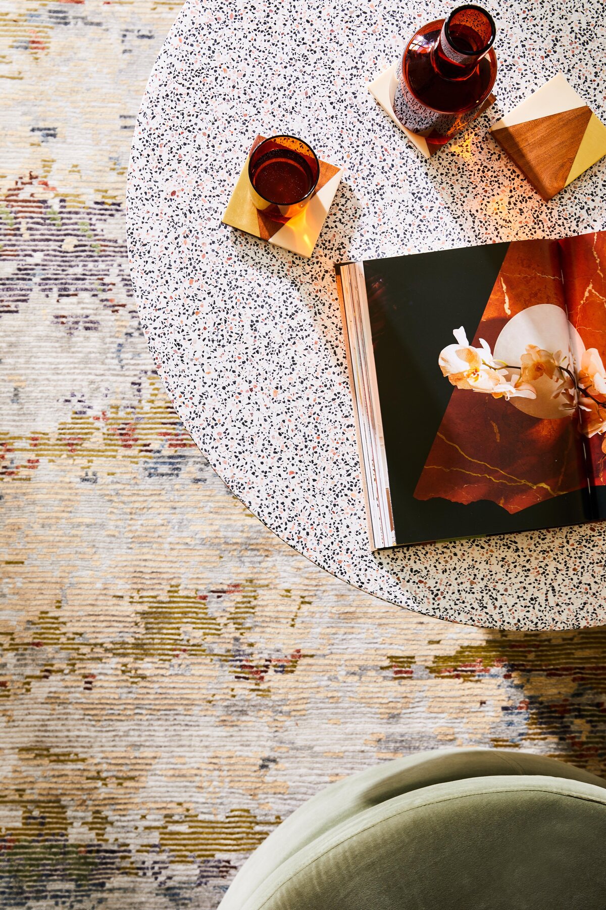 Styled terrazzo coffee table with amber glassware and open book in Elwood mid-century modern apartment