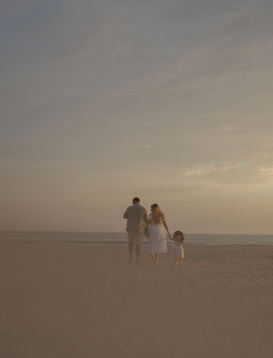 Family playing on the beach at sunset, capturing a candid moment