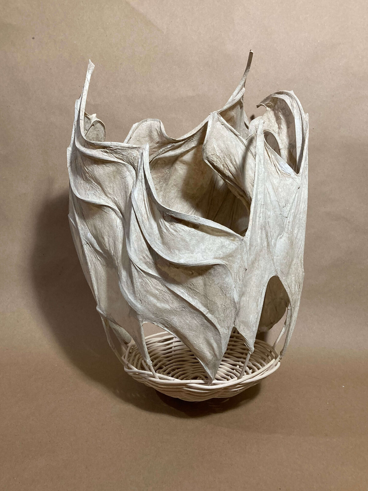 Basket-shaped sculpture crafted from handmade abaca paper over a rattan base, with flowing, sculptural edges.