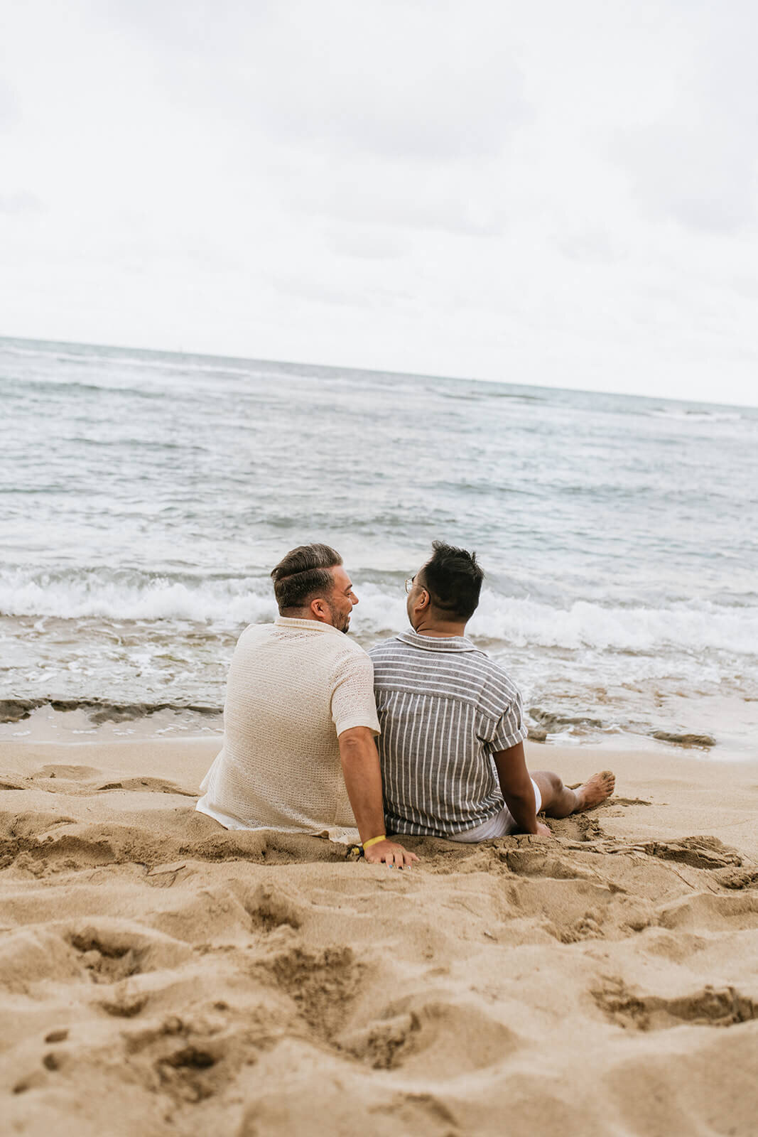 couple-sitting-on-beach-looking-at-water