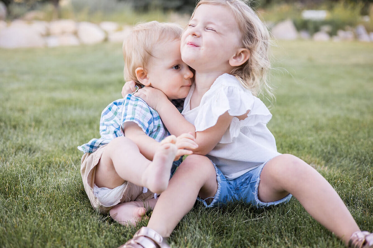 A toddler girl hugging a toddler boy