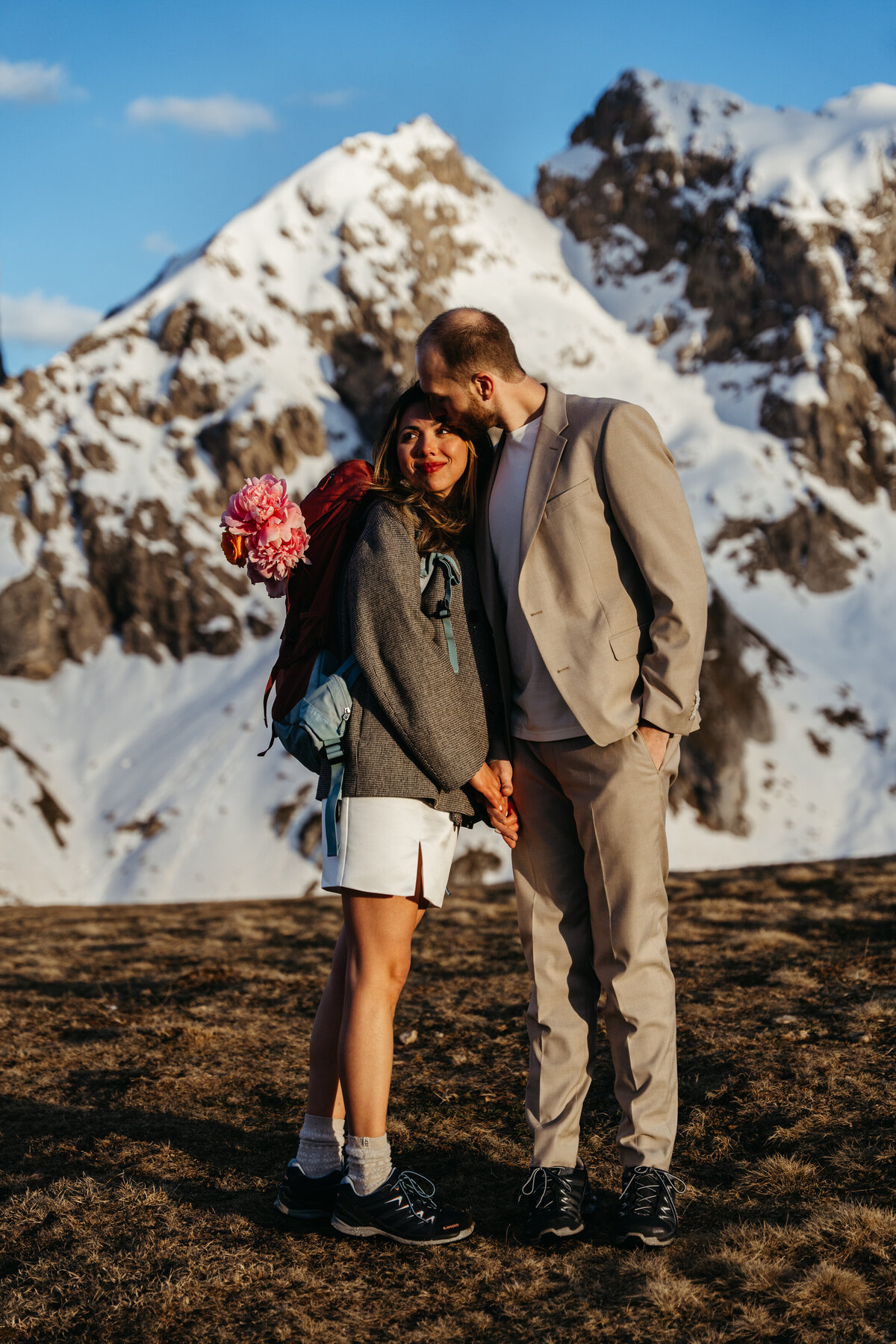 Bride and groom kissing with snowy Dolomites peak behind