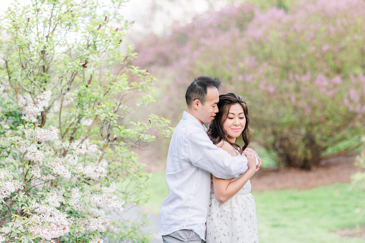 Couple snuggling in front of lilacs representing the best Boston engagement photographer