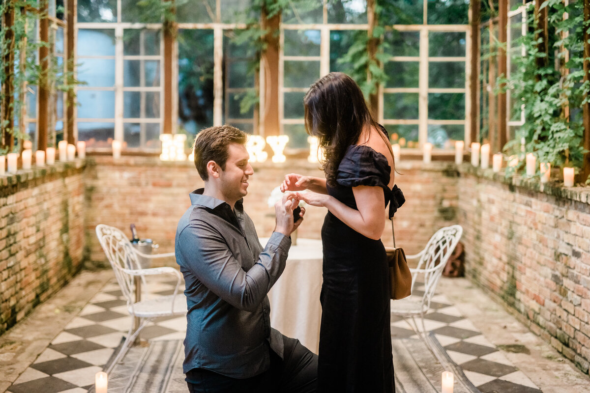 Propose to girlfriend man on one knee putting ring on woman's finger