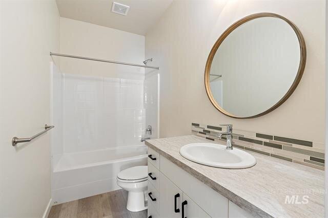 full bathroom with bathtub shower and vanity sink round mirror on wall