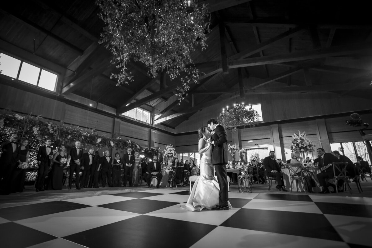 Black and white image of bride and groom dancing.