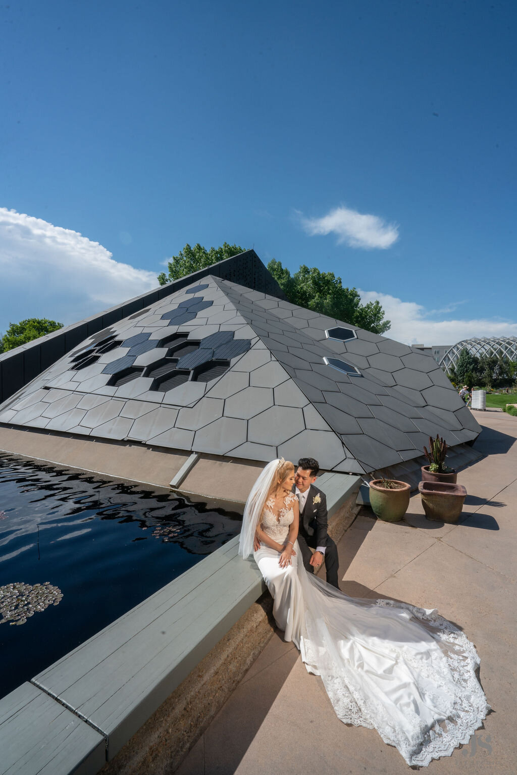 Bride and groom sit by the water at the Denver Botanic Gardens.