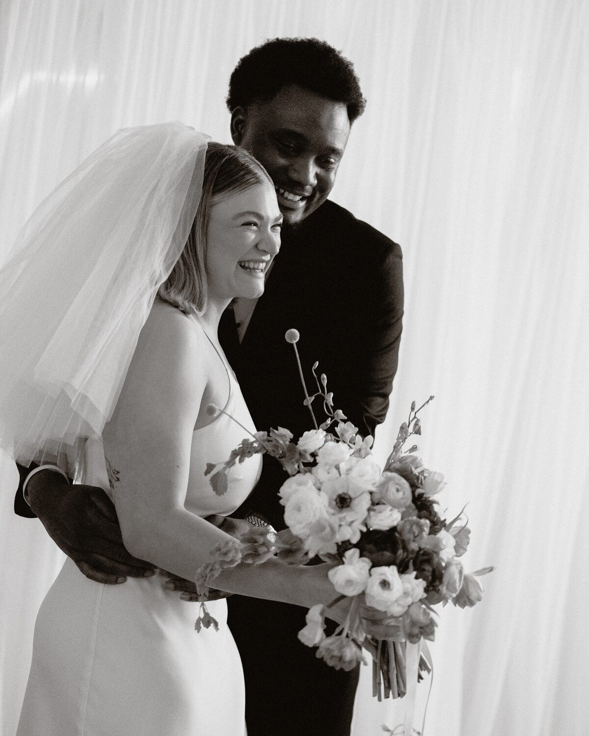 Groom holds on tightly to bride with flowers