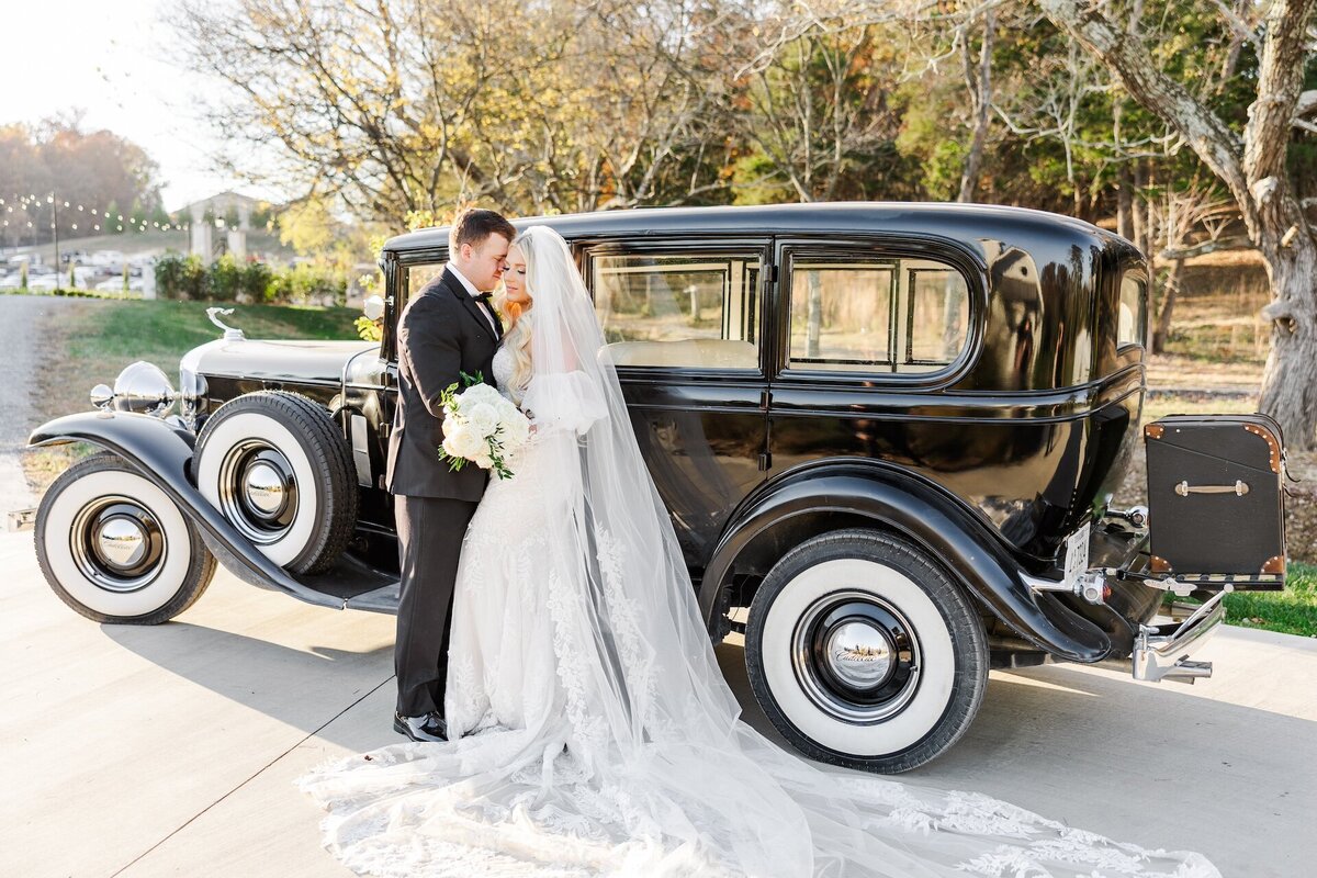bride and groom embracing by a vintage car