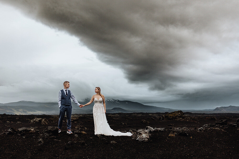 Dramatic elopement photo captures a couple standing against fierce Icelandic winds, their love unyielding in the face of nature’s power.