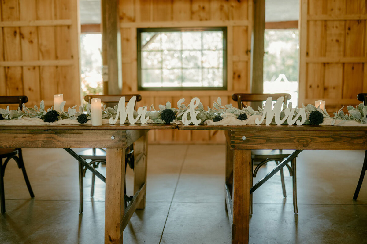 Rustic sweetheart table with "Mr. & Mrs." sign and candles